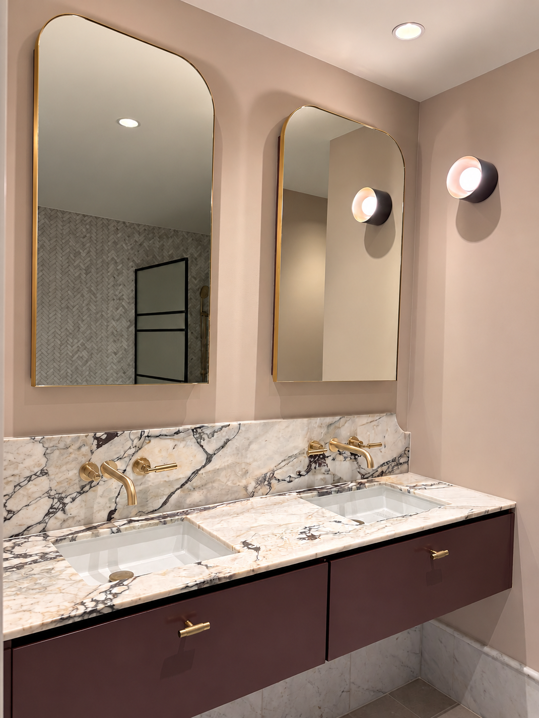 Double vanity with marble top, purple cabinetry and gold fittings